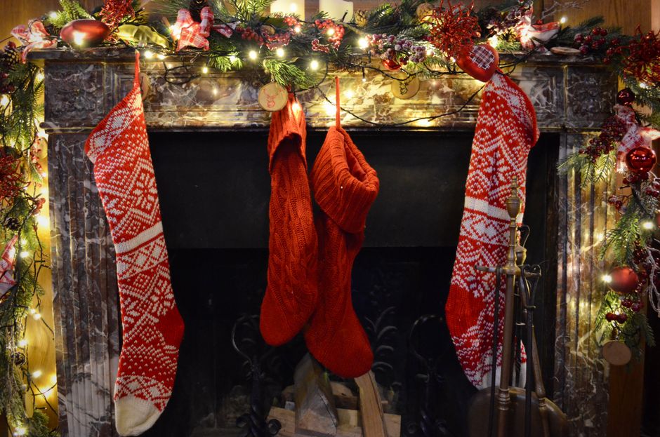 A Christmas mantel with garland, candles, and stockings