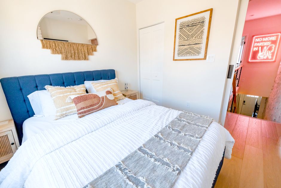 A neatly layered bed with stacked pillows and a folded throw