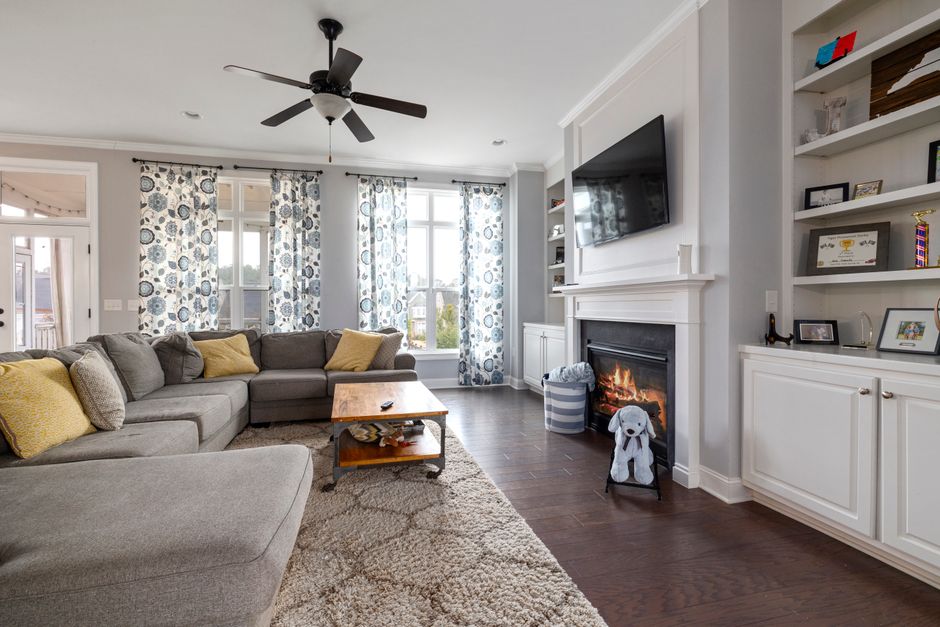 A spacious living room featuring a cozy fireplace, modern sofa, and elegant decor with natural light.