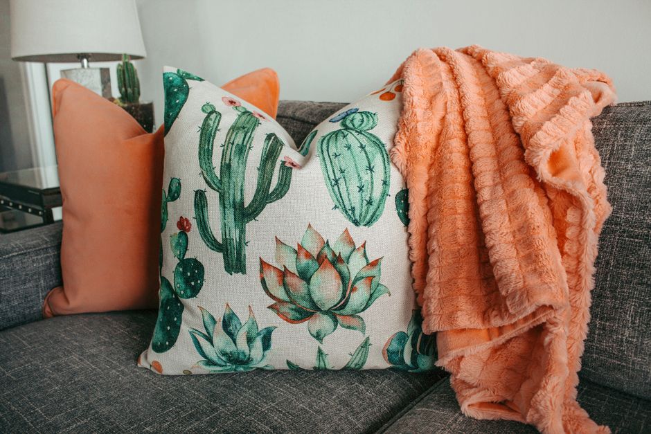 A sofa layered with mixed-texture cushions and a knit throw