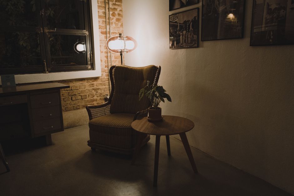 A cozy reading nook with an armchair, plant, and warm light