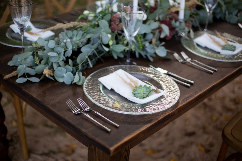 A layered place setting with plates, a cloth napkin, and greenery
