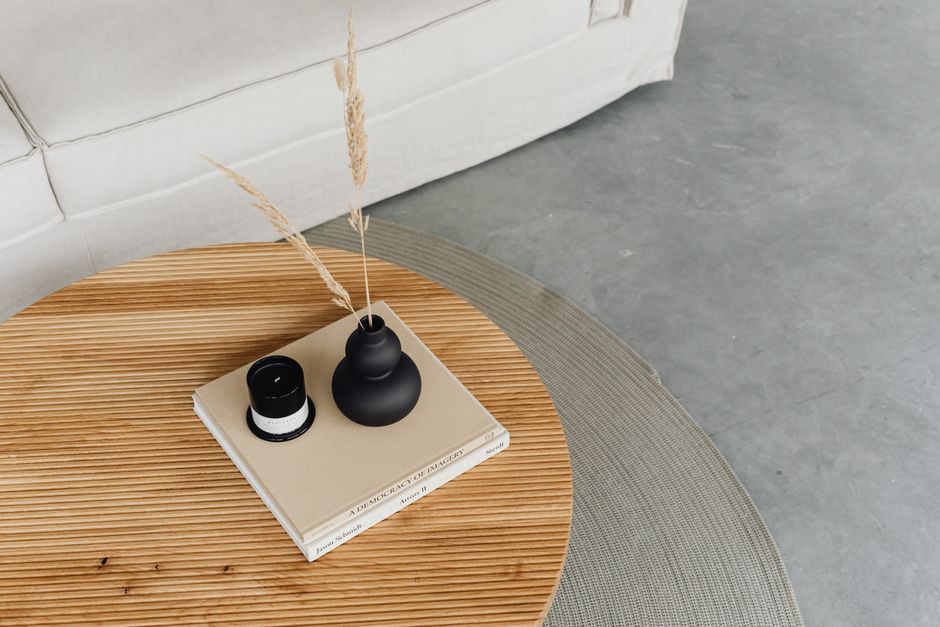 A vase with greenery beside a stack of books on a coffee table