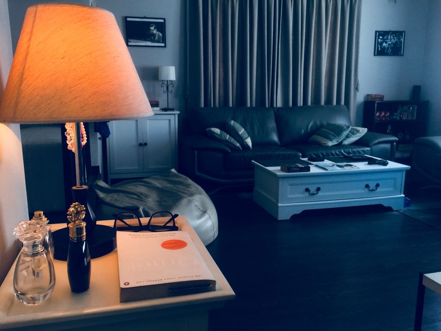 A warm table lamp glowing on a wood side table in a cozy living room setting