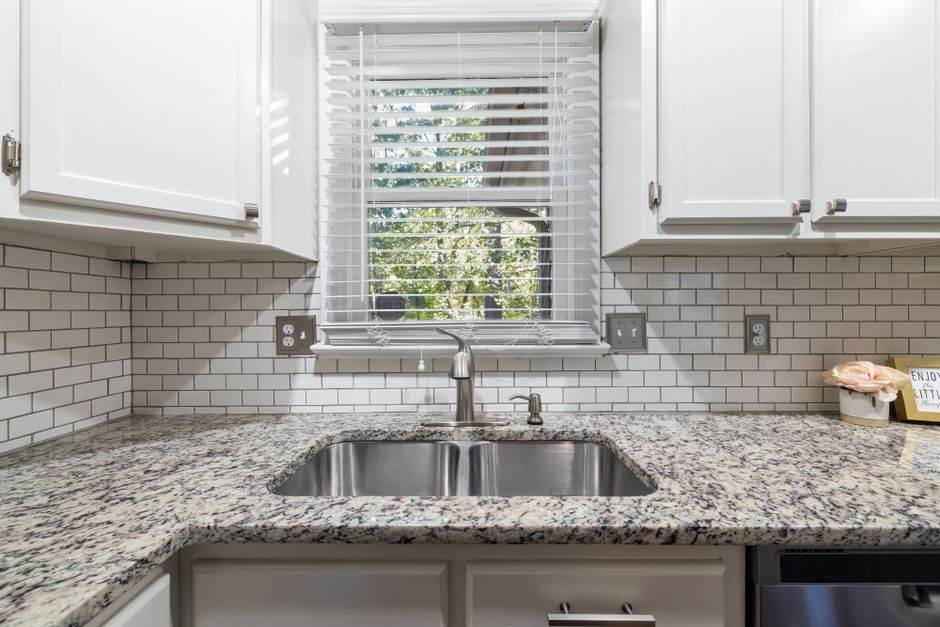 Spacious kitchen showcasing sleek cabinets, granite countertop, and a stainless steel sink.