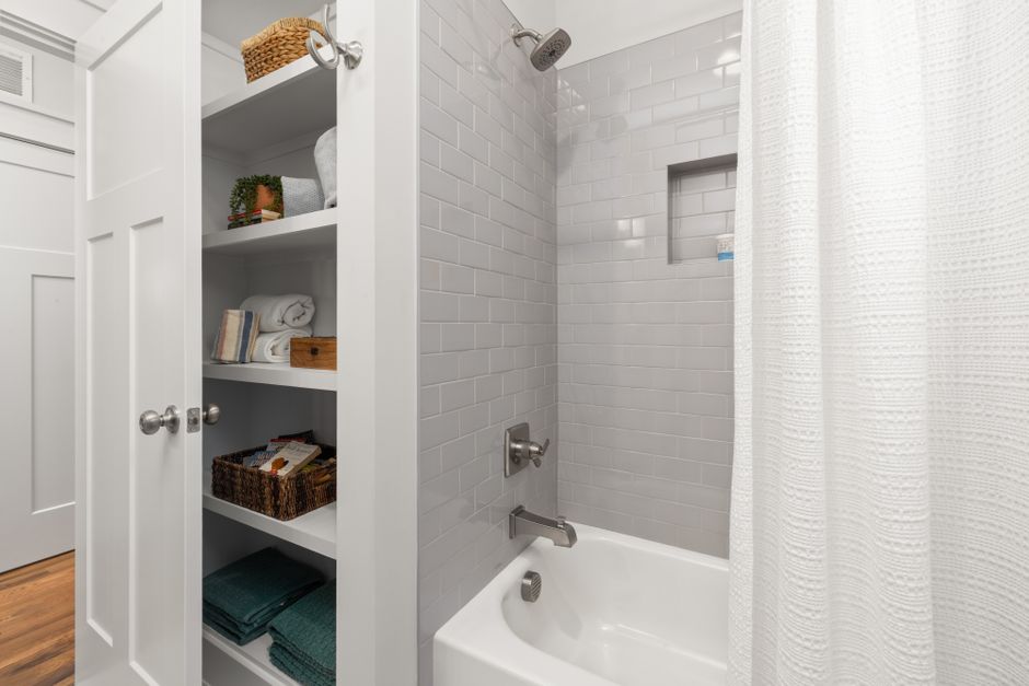 Organized bathroom shelves with baskets and rolled towels