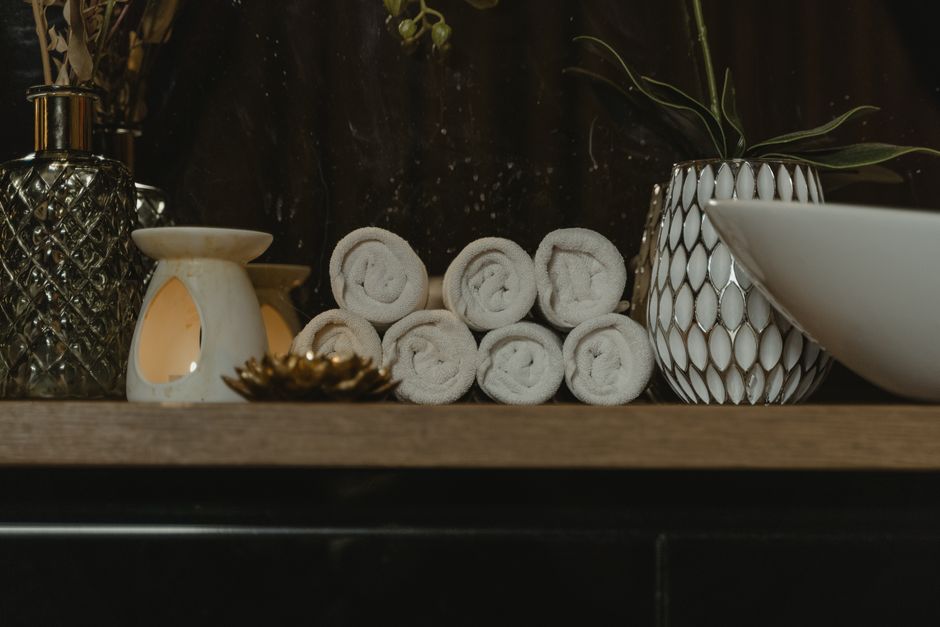 A spa-like bathroom with candles, rolled towels, and a plant