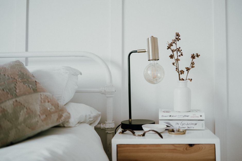 Nightstand styled with a tray, lamp, and small stack of books