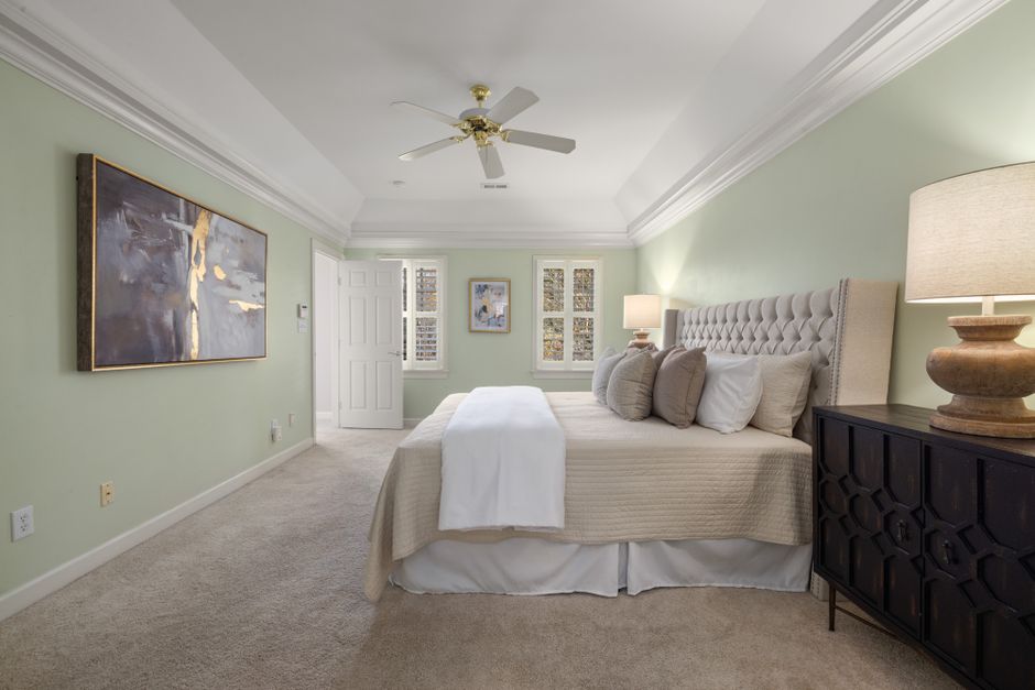 Sage green accent wall behind a bed with neutral linens