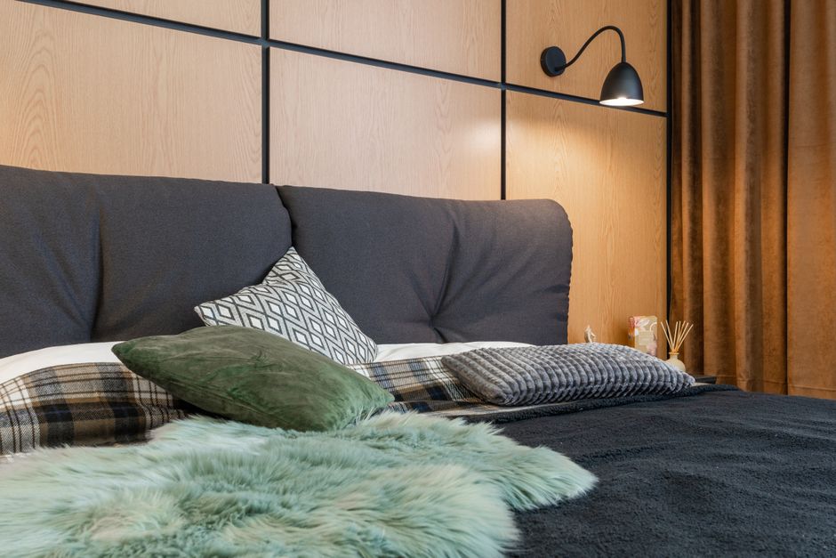 Interior of bedroom with cushions placed on soft bed under lamp hanging above bedside with aroma sticks
