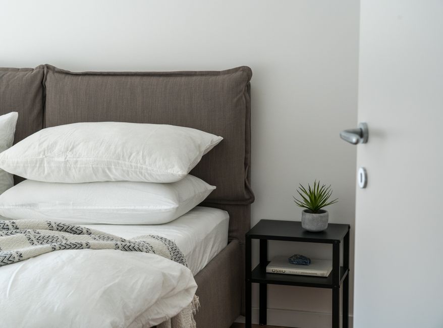 Small guest bedroom with a neatly made bed and warm neutral bedding