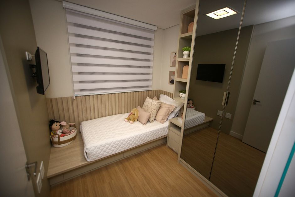 Small bedroom with bed against wall and space-saving furniture arrangement