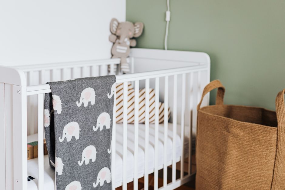 Stylish nursery featuring a cozy white crib with a cute elephant blanket.