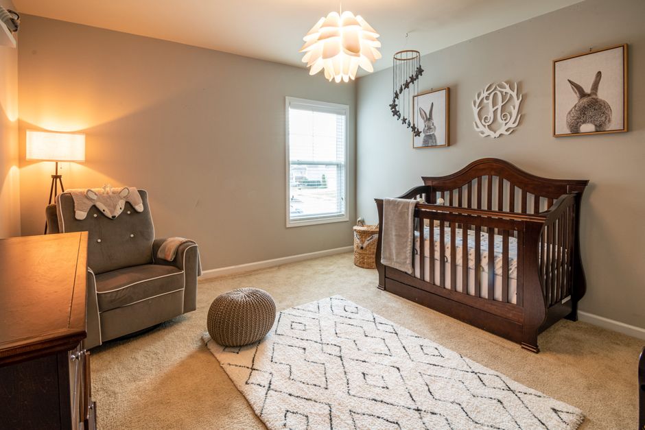 Soft neutral nursery with a wooden crib, rug, and reading chair