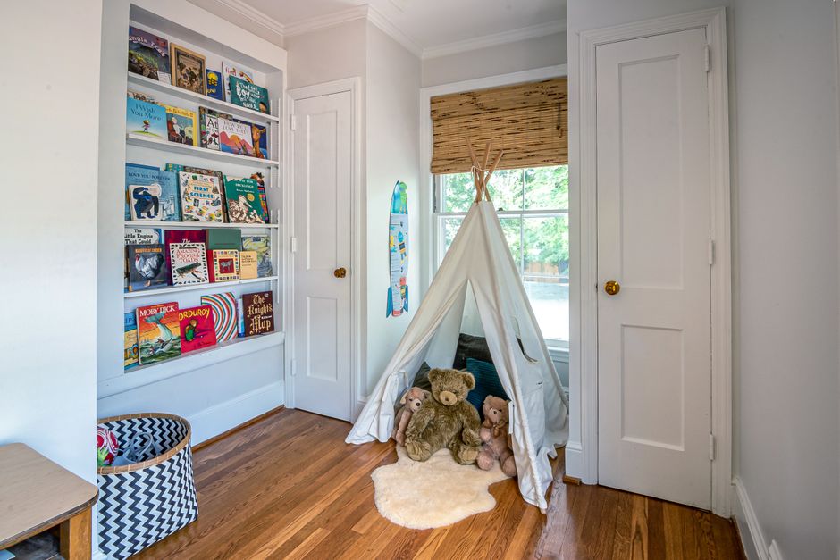 Cozy nursery reading nook with an upholstered chair and small bookshelf