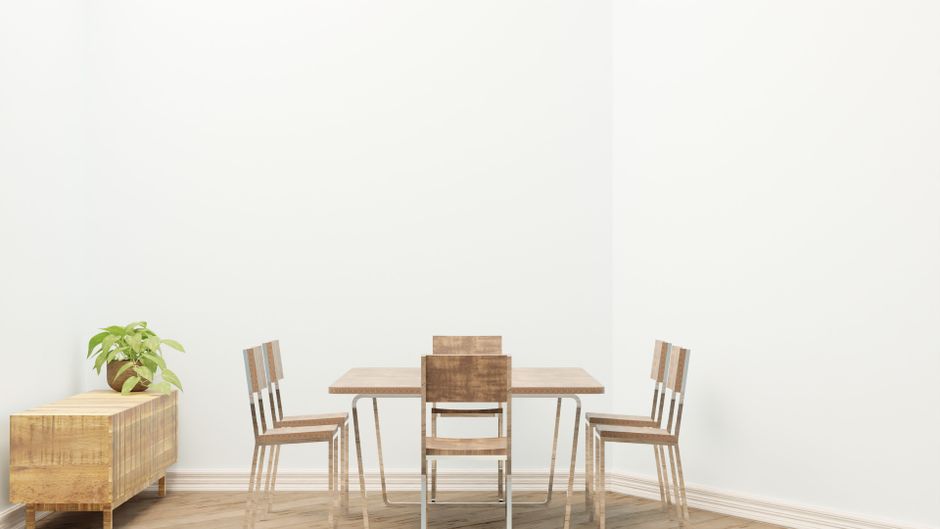 Simple dining room setup featuring wooden table and chairs with a potted plant for decoration.