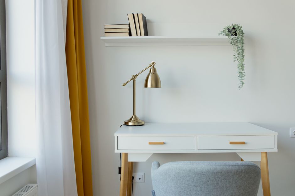 Stylish home office desk featuring a gold lamp, white decor, and minimalist aesthetic.