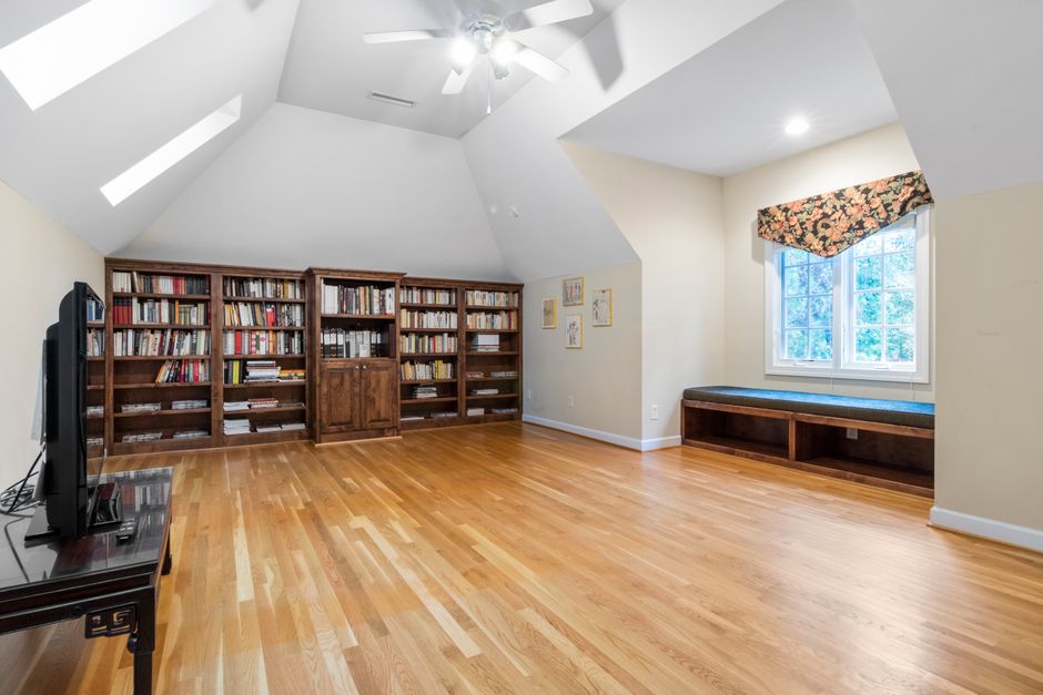 Attic reading nook built into a dormer window with cushions and a small bookshelf