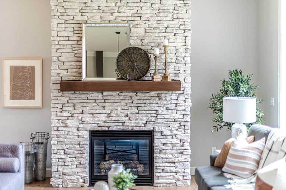 Fireplace mantel styled with a leaning mirror, candles, and greenery