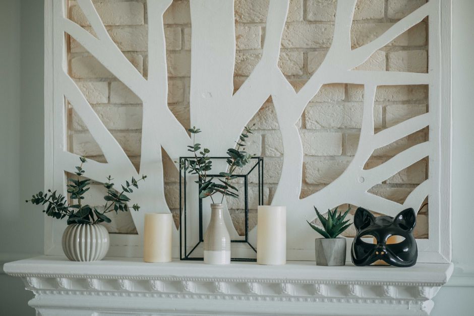 Minimalist fireplace mantel styled with stacked books and taper candles