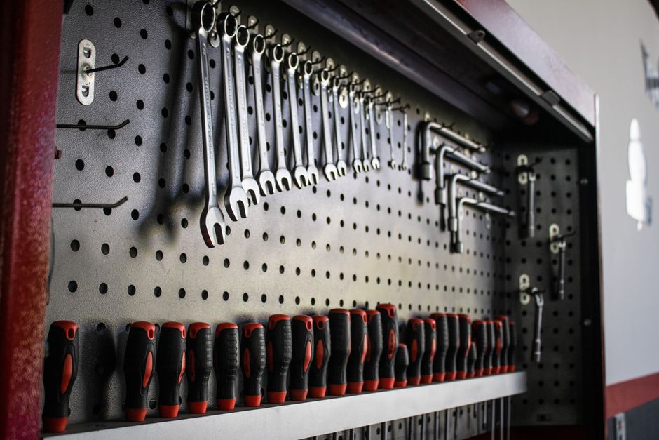 Pegboard wall system holding hand tools, hooks, and small bins