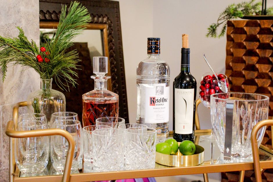 Small bar cart styled with glassware, bottles, and a tray