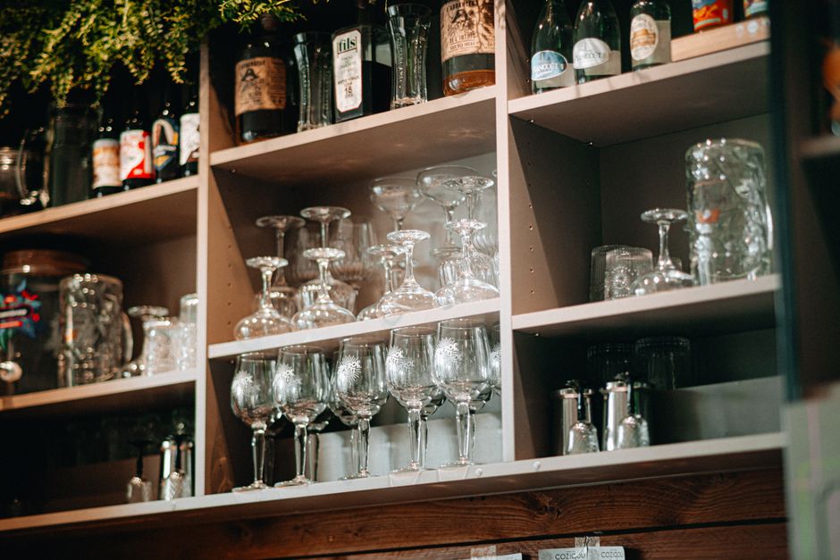 Styled home bar shelf with bottles, glasses, and a small plant