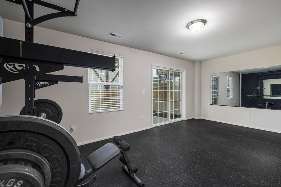 Small home gym room with black rubber flooring and a full-length mirror