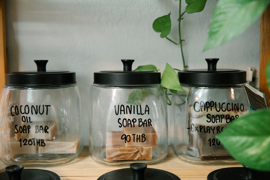 Wall-mounted shelf holding glass jars and labeled fabric bins for laundry supplies