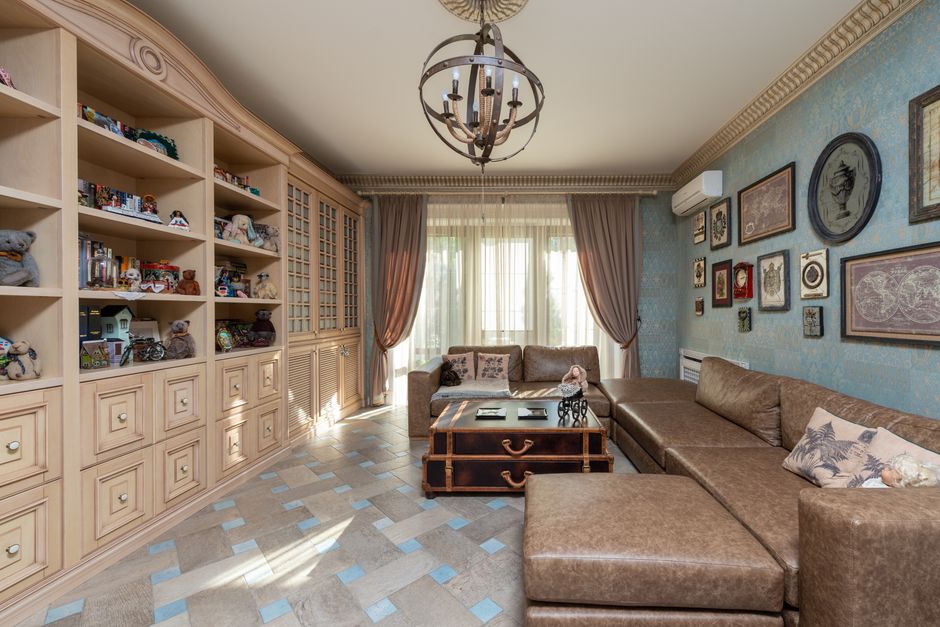 Spacious living room featuring classic decor with bookshelves, leather sofa, and wall art.