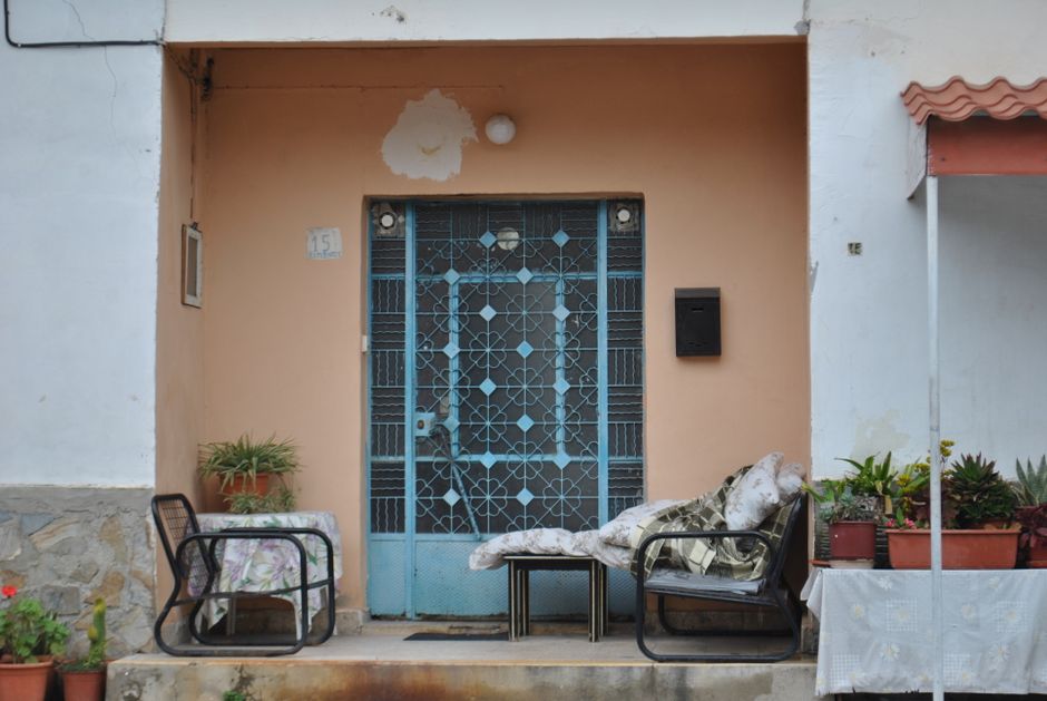 Cozy porch with chairs and plants at a Mediterranean style home entrance.