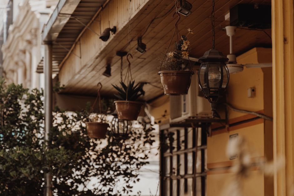 Small porch with railing planters and hanging plant baskets