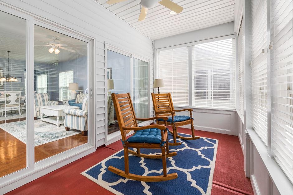 Inviting sunroom with rocking chairs and glass doors leading to a stylish interior living space.