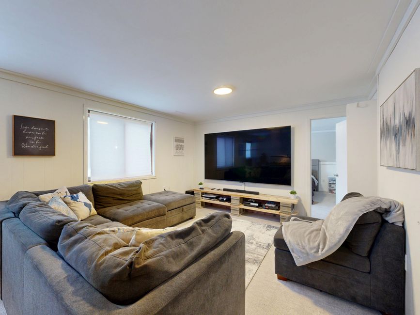 Spacious living room featuring a large flat-screen TV, gray sectional sofa, and cozy decor.