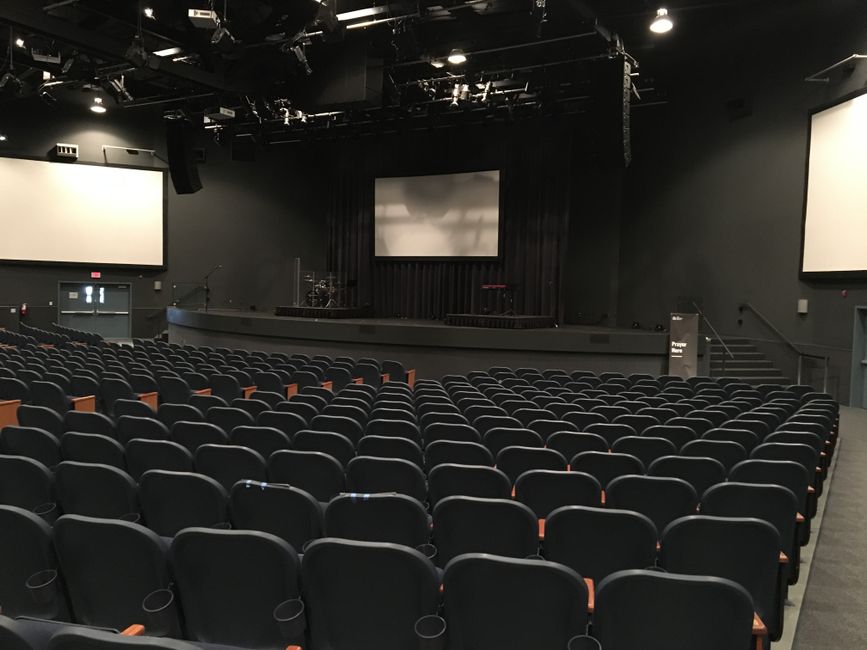 Theater-style seating layout in a darkened room with screen in view